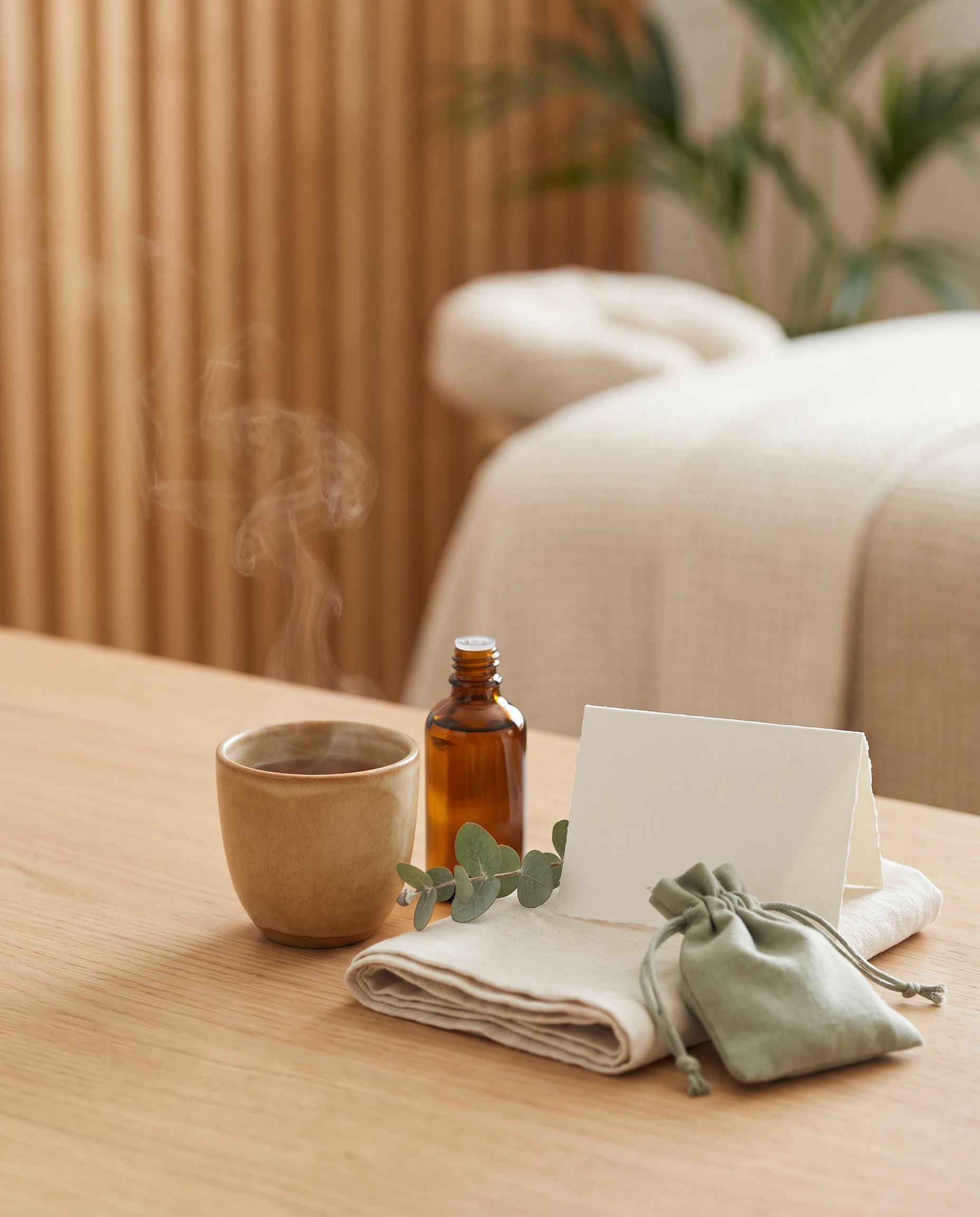 Herbal tea, an unlabelled amber bottle, linen and a blank guidance card in a calm treatment setting.