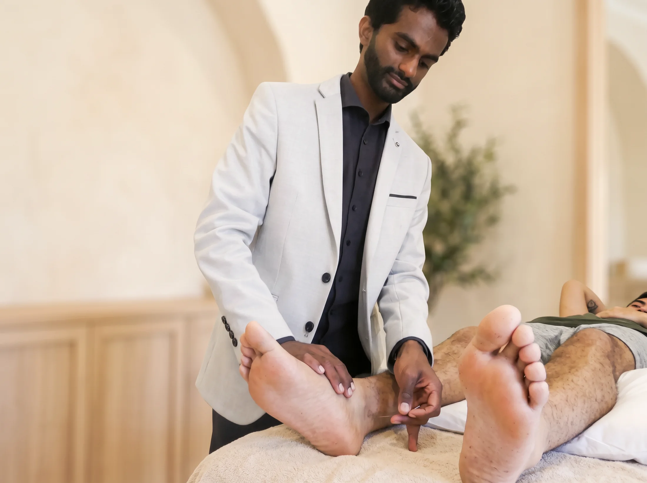 Ahil Ganesan placing an acupuncture needle in a patient's foot